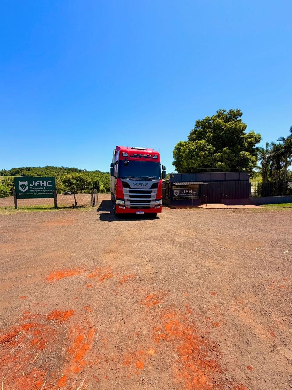 Caminhão vermelho na base da JFHC Transportes